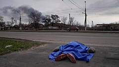 A body lies covered by a tarp in the street in Mariupol on 7 March 2022