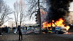 Police vans are on fire as counter-protesters react during a counter-protest in the park Sveaparken in Orebro, south-centre Sweden on April 15, 2022.