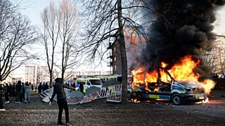 Police vans are on fire as counter-protesters react during a counter-protest in the park Sveaparken in Orebro, south-centre Sweden on April 15, 2022.