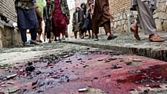 Taliban fighters stand guard on a blood-stained street at the site of the explosion.