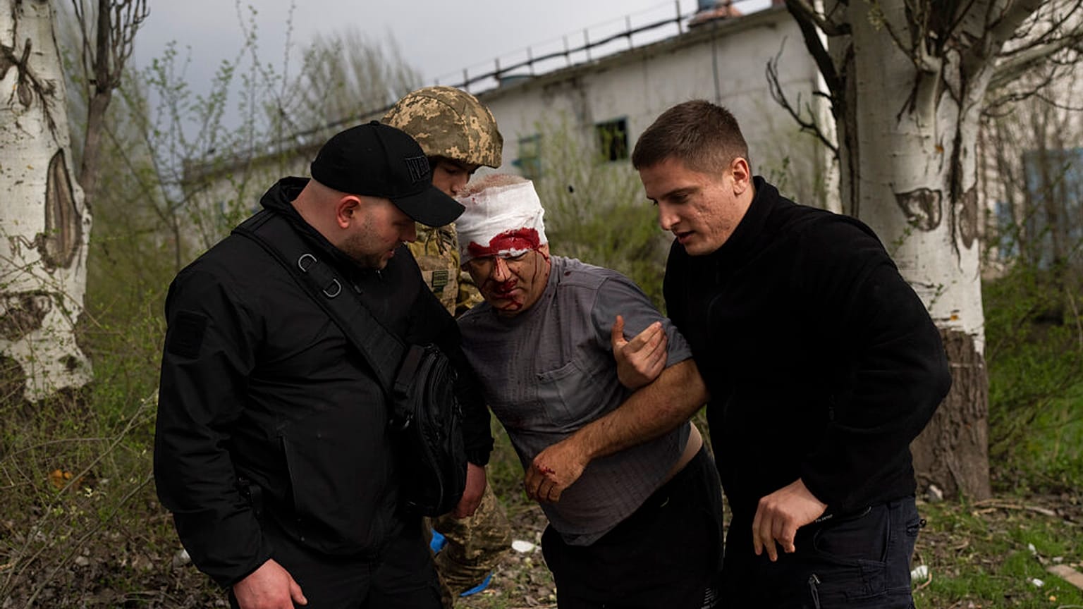 Un membre des forces de sécurité aide un homme blessé après un bombardement russe d'une usine à Kramatorsk, dans l'est de l'Ukraine, mardi 19 avril 2022