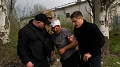 Un membre des forces de sécurité aide un homme blessé après un bombardement russe d'une usine à Kramatorsk, dans l'est de l'Ukraine, mardi 19 avril 2022