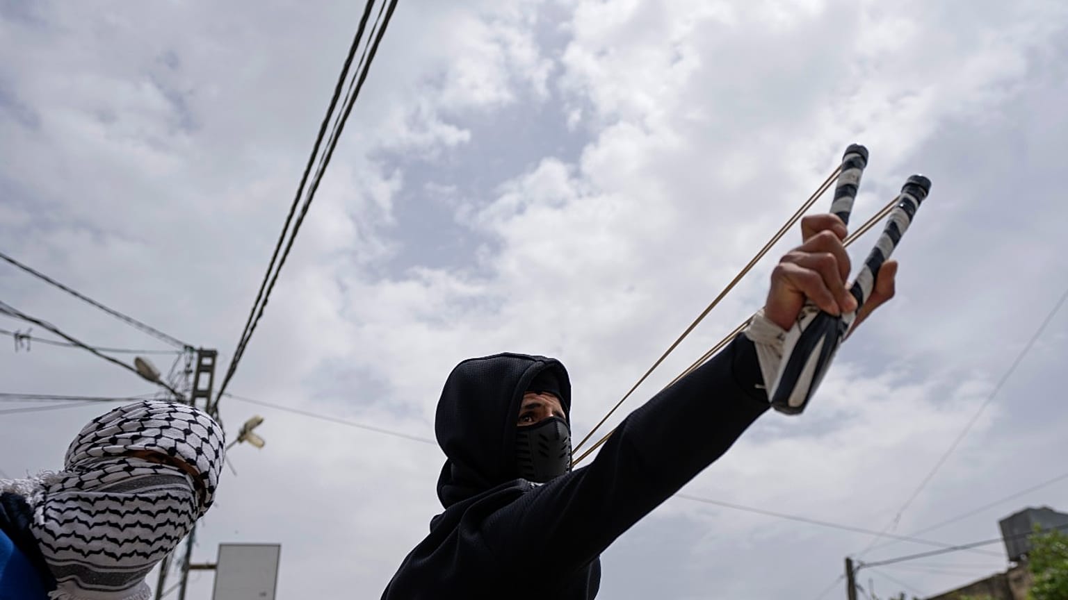 متظاهر فلسطيني يستخدم المقلاع خلال مواجهات مع الجيش الإسرائيلي في قرية برقة، بالقرب من نابلس، الضفة الغربية.