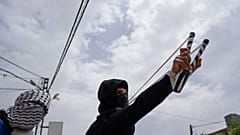 متظاهر فلسطيني يستخدم المقلاع خلال مواجهات مع الجيش الإسرائيلي في قرية برقة، بالقرب من نابلس، الضفة الغربية.