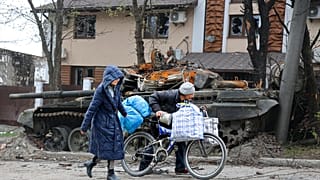 Жители Мариуполя идут мимо танка, уничтоженного во время боя. 19 апреля 2022 г.