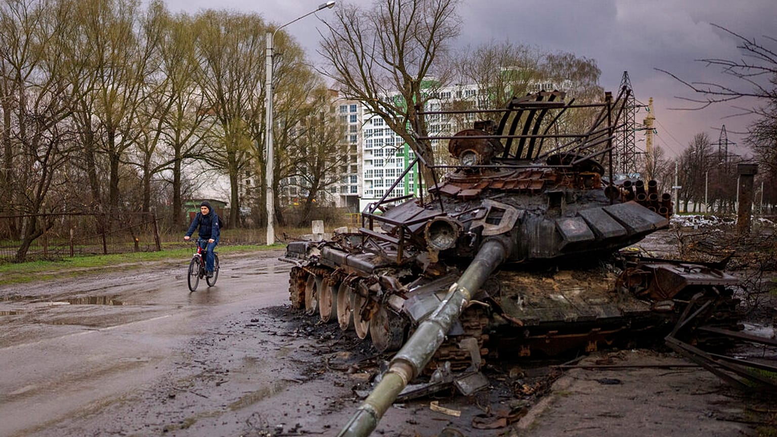 DUn homme à vélo à côté d'un char russe détruit, à Chernihiv (Ukraine), le 21/04/2022