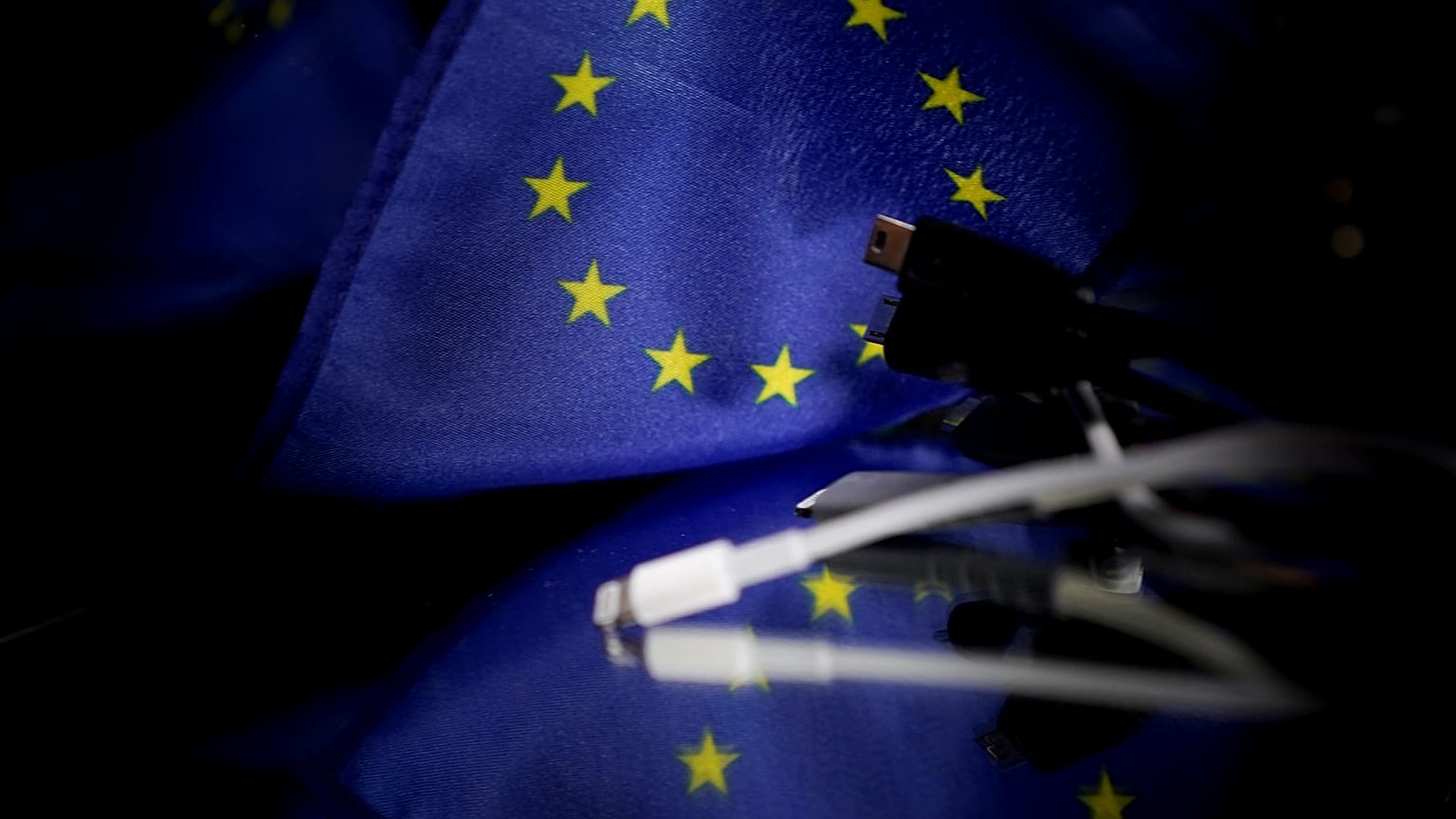 A picture taken on February 6, 2020 in Brussels shows plugs for mobile charger next to a European flag. 