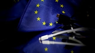 A picture taken on February 6, 2020 in Brussels shows plugs for mobile charger next to a European flag. 