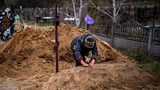 Γυναίκα γονιατίζει σε αυτοσχέδιο τάφο στην πόλη Μπούτσα στα περίχωρα του Κιέβου