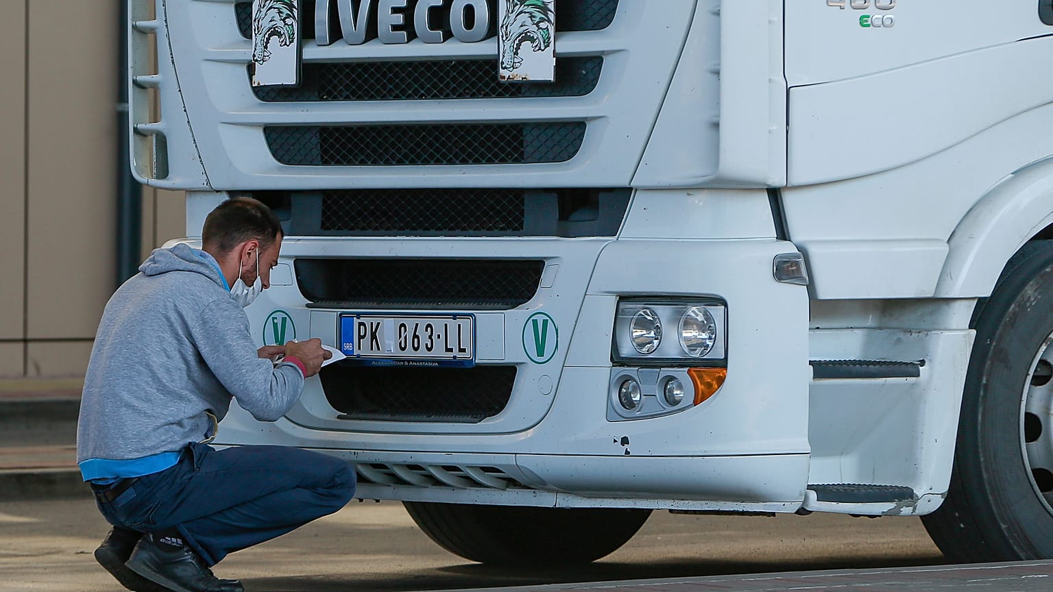 A truck driver places stickers on number plates at the Merdare border crossing on Monday, Oct. 4, 2021.