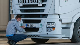 A truck driver places stickers on number plates at the Merdare border crossing on Monday, Oct. 4, 2021.
