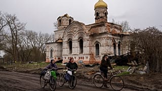 Vecinos de Lukashivka (Ucrania) pasan frente a la iglesia, destruida por los ataques rusos.
