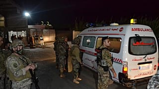 Libanesische Soldaten wachen am Eingang des Hafens von Tripoli während Krankenwagen Opfer des Bootsungklücks abtransportieren.