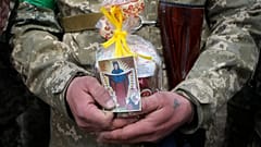 A Ukrainian soldier holds an Easter cake and an icon during a blessing ceremony on Easter eve at a military position outside Kyiv, 23 April 2022