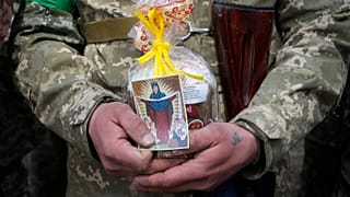 A Ukrainian soldier holds an Easter cake and an icon during a blessing ceremony on Easter eve at a military position outside Kyiv, 23 April 2022