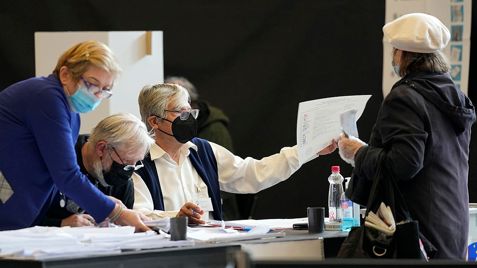 A voter is passed a ballot at a polling station for early voting in Ljubljana on 21 April 2022