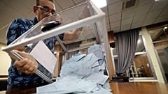 Un assesseur dans un bureau de vote de l'île de la Réunion, dans l'océan Indien, en train de vider une urne, le 24 avril 2022.  
