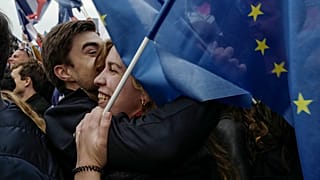 Anhänger:innen des französischen Präsidenten mit EU-Flagge warten auf seine Rede am Wahlabend in Paris