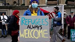 A demonstrator holds a placard saying 'Refugees always welcome' during an anti-war march, in London, Sunday, March 6, 2022. 
