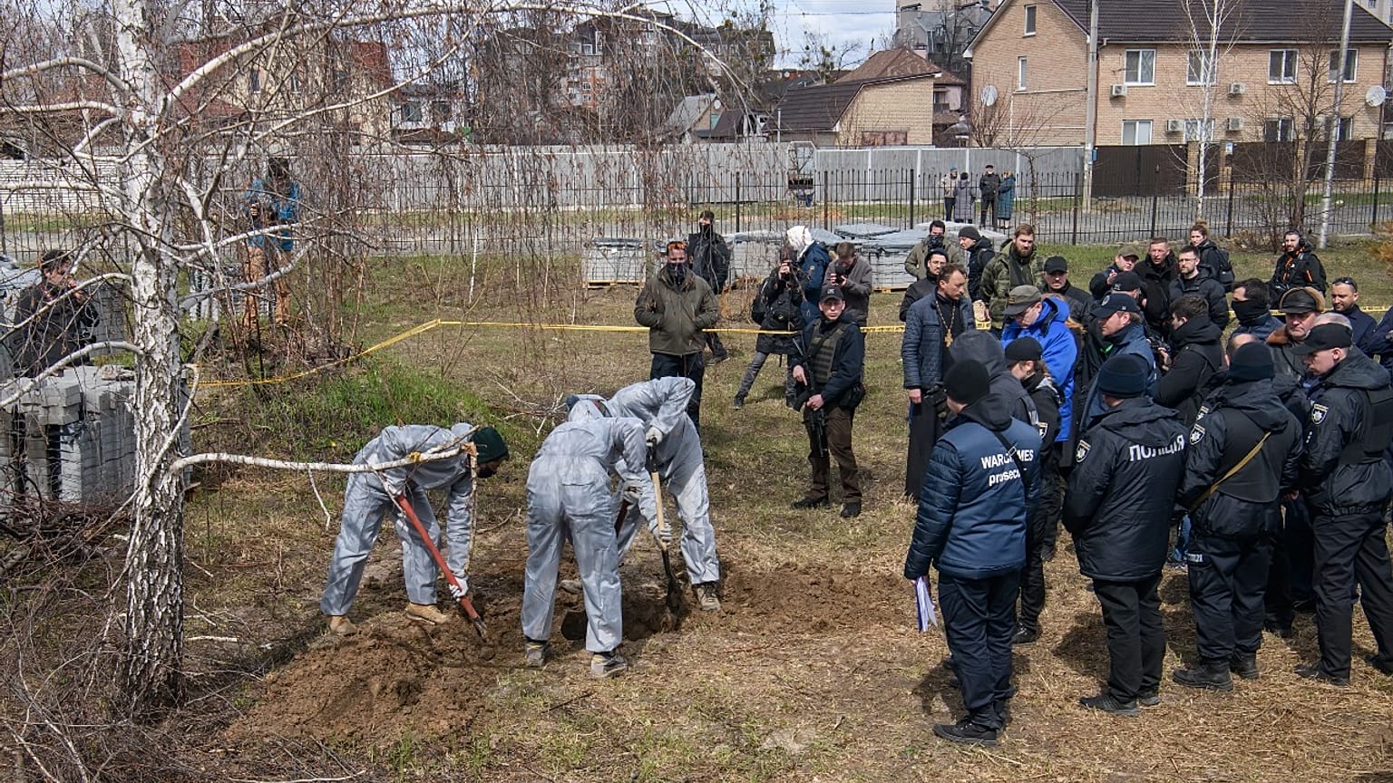French forensics investigators, in Ukraine to investigate war crimes amid Russia's invasion, stand next to a mass grave in Bucha, near Kyiv, Ukraine, April 12, 2022.