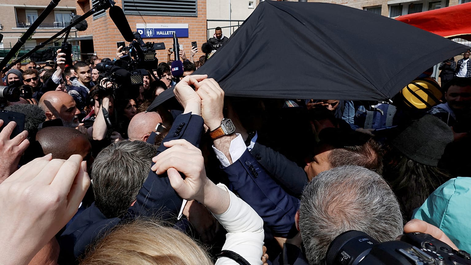 Domates saldırısına uğrayan Fransa Cumhurbaşkanı Macron'un korumaları, yakın çevresini güvenlik altına alarak başının üstünde şemsiye açtı