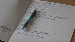 Schulheft mit ein paar ersten Sätzen auf Deutsch