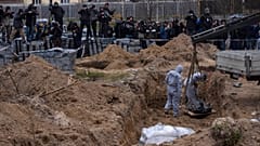 Cemetery workers exhume the corpse of a civilian killed in Bucha from a mass grave, in the outskirts of Kyiv, Ukraine, Wednesday, April 13, 2022.