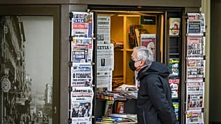 Un passant devant un kiosque à journaux en décembre 2021 à Athènes (Grèce) 
