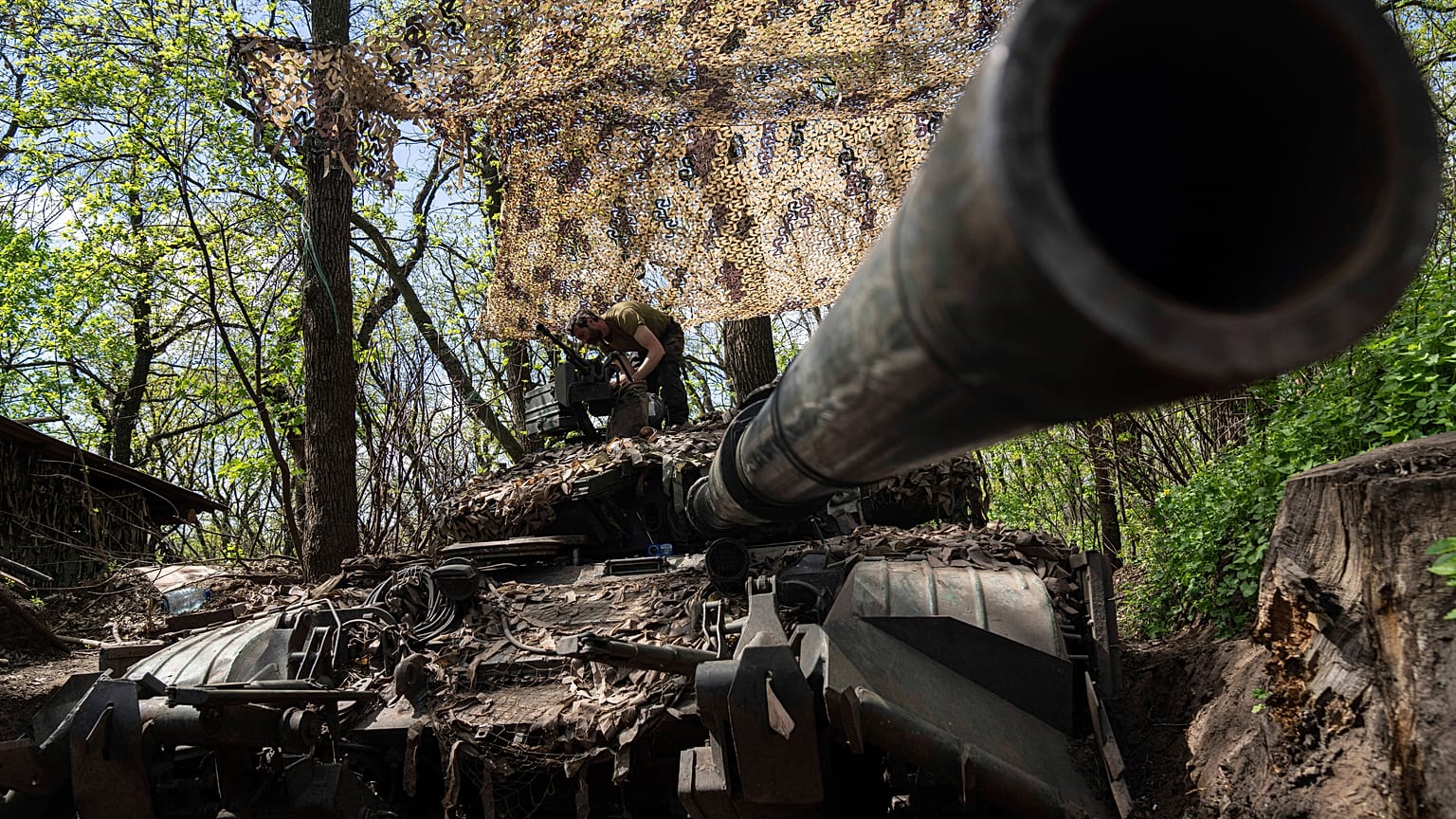 Украинский военнослужащий устанавливает пулемёт на танк в Донецкой области