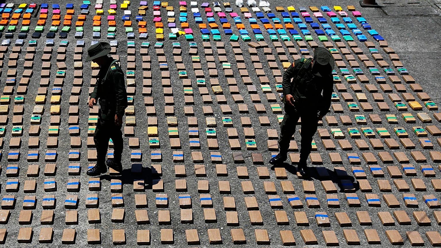 In this Thursday, 10 August 2017 file photo, police officers walk among packages of seized cocaine at the Pacific port of Buenaventura, Colombia