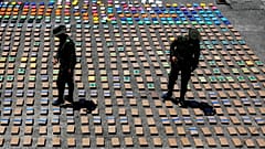 In this Thursday, 10 August 2017 file photo, police officers walk among packages of seized cocaine at the Pacific port of Buenaventura, Colombia