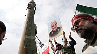 متظاهرون في طهران بمناسبة "يوم القدس" يقفون قرب صاروخ "شهاب3" 