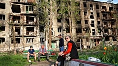Residentes locales sentados en el patio de su edificio dañado en Mariupol, en el este de Ucrania, el viernes 29 de abril de 2022