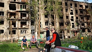 Местные жители на фоне разрушенного дома в Мариуполе, 29 апреля 2022 г.