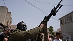 مقاتل فلسطيني ملثم يطلق النار في الهواء خلال جنازة يحيى عدوان في قرية عزون بالضفة الغربية، بالقرب من قلقيلية. 2022/04/30
