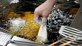 Рыбу в кляре бросают в горячее подсолнечное масло для приготовления фиш-энд-чипс, Лондон