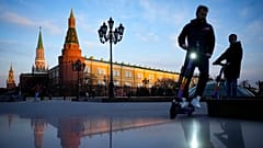 FILE - Youth ride scooters in Manezhnaya Square near Red Square and the Kremlin after sunset in Moscow, Russia, on April 20, 2022