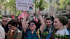 Demonstrators hold bouquet with sign reading  "Work tires even the donkeys, Let's stay beavers" during a May Day demonstration march.