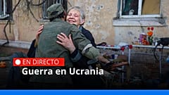 Una mujer local abraza a un soldado de la milicia cerca de un edificio de apartamentos dañado en Mariúpol