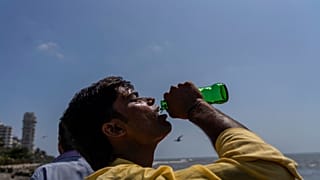 Un homme boit un soda au cours d'une promenade sur les côtes de la mer d'Arabie à Mumbai, Inde (1er mai 2022).
