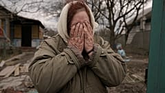 Женщина плачет у ворот своего разрушенного дома в Андреевке, 6 апреля 2022. 