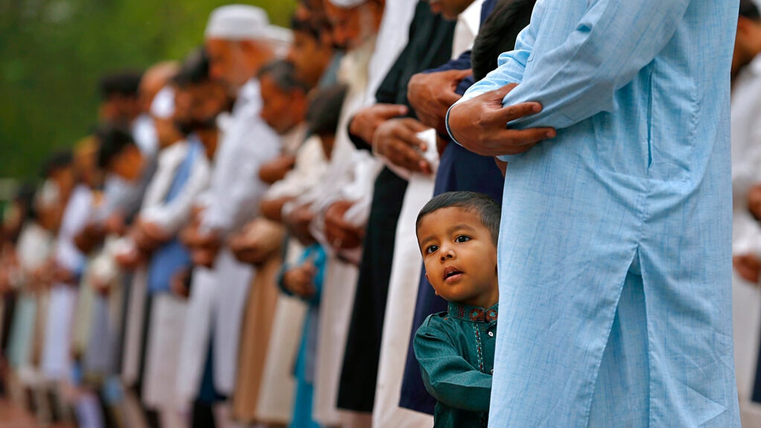 طفل يقف بجانب والده وهو يؤدي صلاة عيد الفطر بمناسبة انتهاء شهر رمضان في روالبندي، باكستان، الثلاثاء 3 مايو 2022 