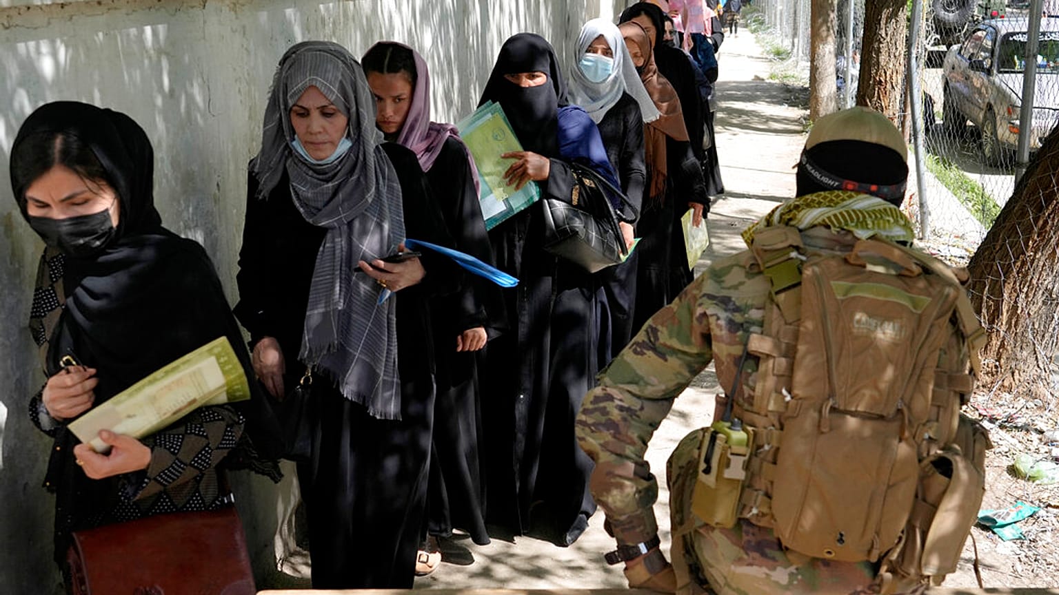 Un taliban monte la garde pendant que des femmes font la queue devant le bureau des passeports à Kaboul