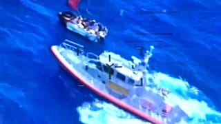 Buque de la Guardia Costera muy cerca del velero, que está visiblemente lleno de gente
