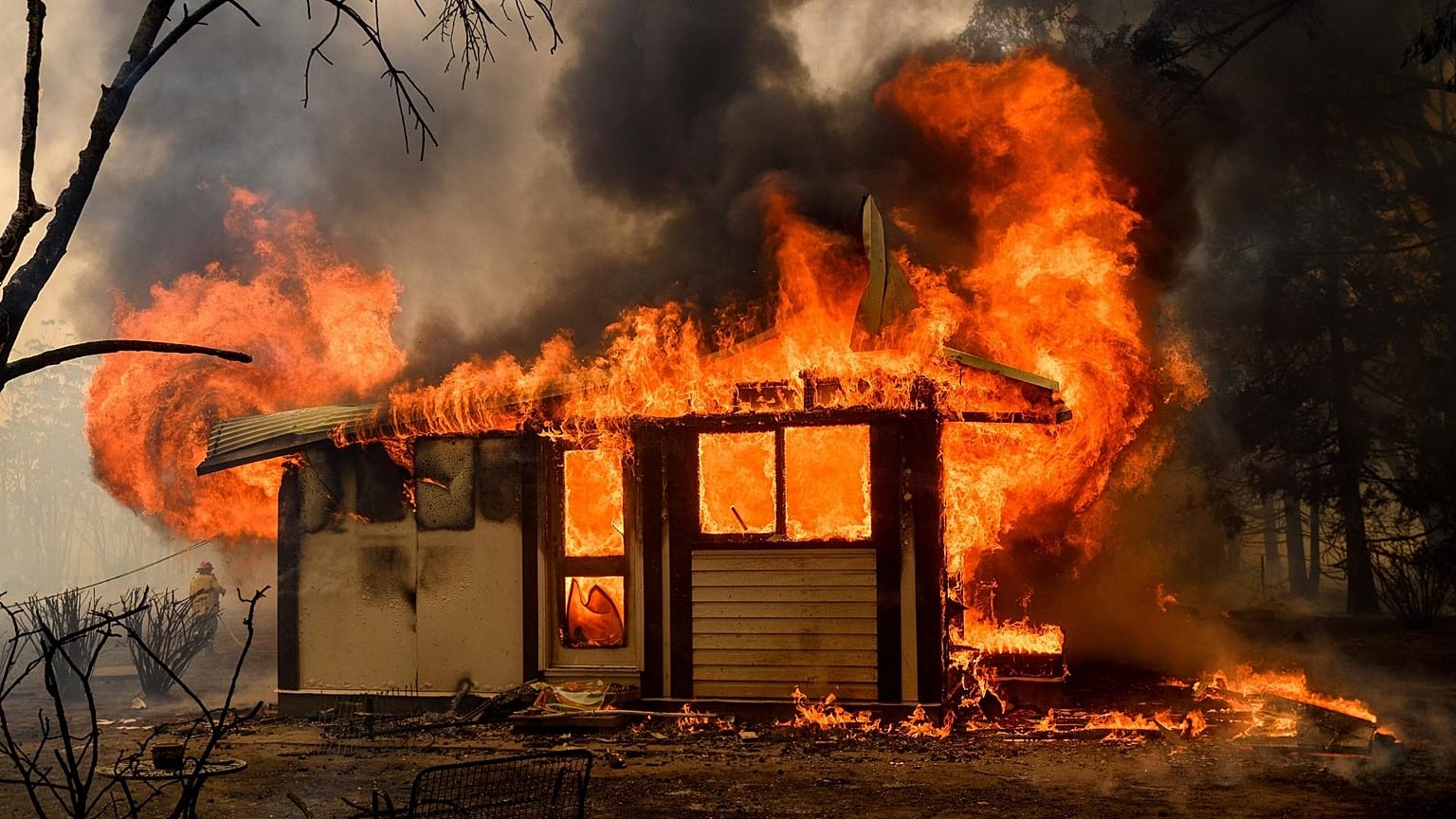 Flames from the Morton Fire consume a home near Bundanoon, Australia in 2020. 