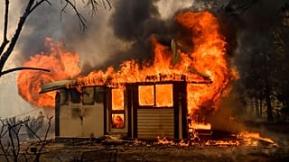 Flames from the Morton Fire consume a home near Bundanoon, Australia in 2020. 