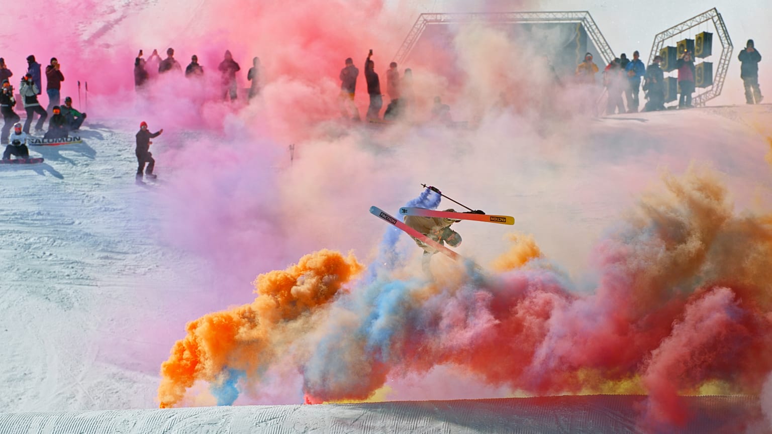 A freeskier mid-air above a jump surrounded by colour