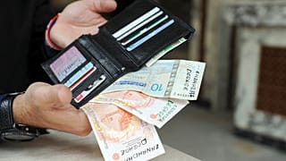  الدينار التونسي كُتب عليه شعارات تطالب حزب النهضة الإسلامي بالتنحي عن السلطة في محفظته في مقهى بالعاصمة تونس، يوم 15 نوفمبر 2013.