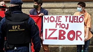 A police officer stands guard in front of women's rights activists during an anti-abortion march in Zagreb in May 2021.