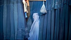 زنی در کابل منتظر است تا برقع تازه دوخته شده خود را امتحان کند، سال ۲۰۱۳ میلادی